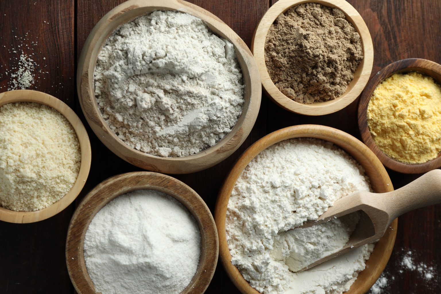 different types of flour in bowls on wooden table